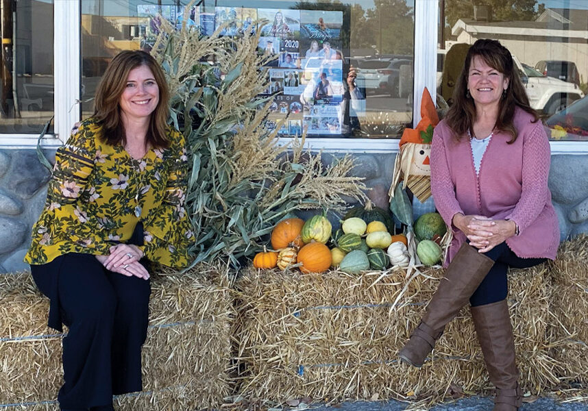 women sitting on hay bale with decorations